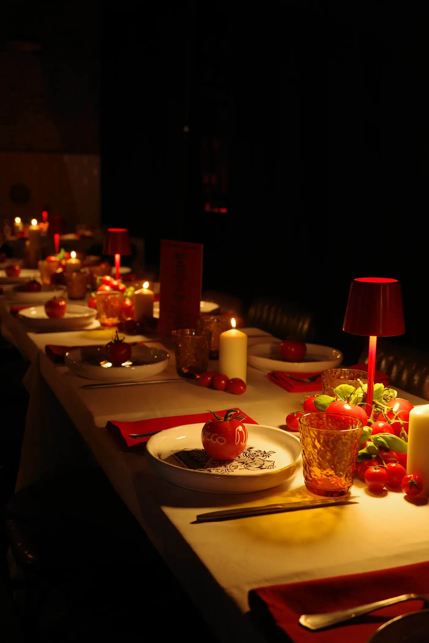La tavolata della private dinner Cut Wrong da Fradiavolo Sempione: lampade rosse, candele e pomodori sui piatti